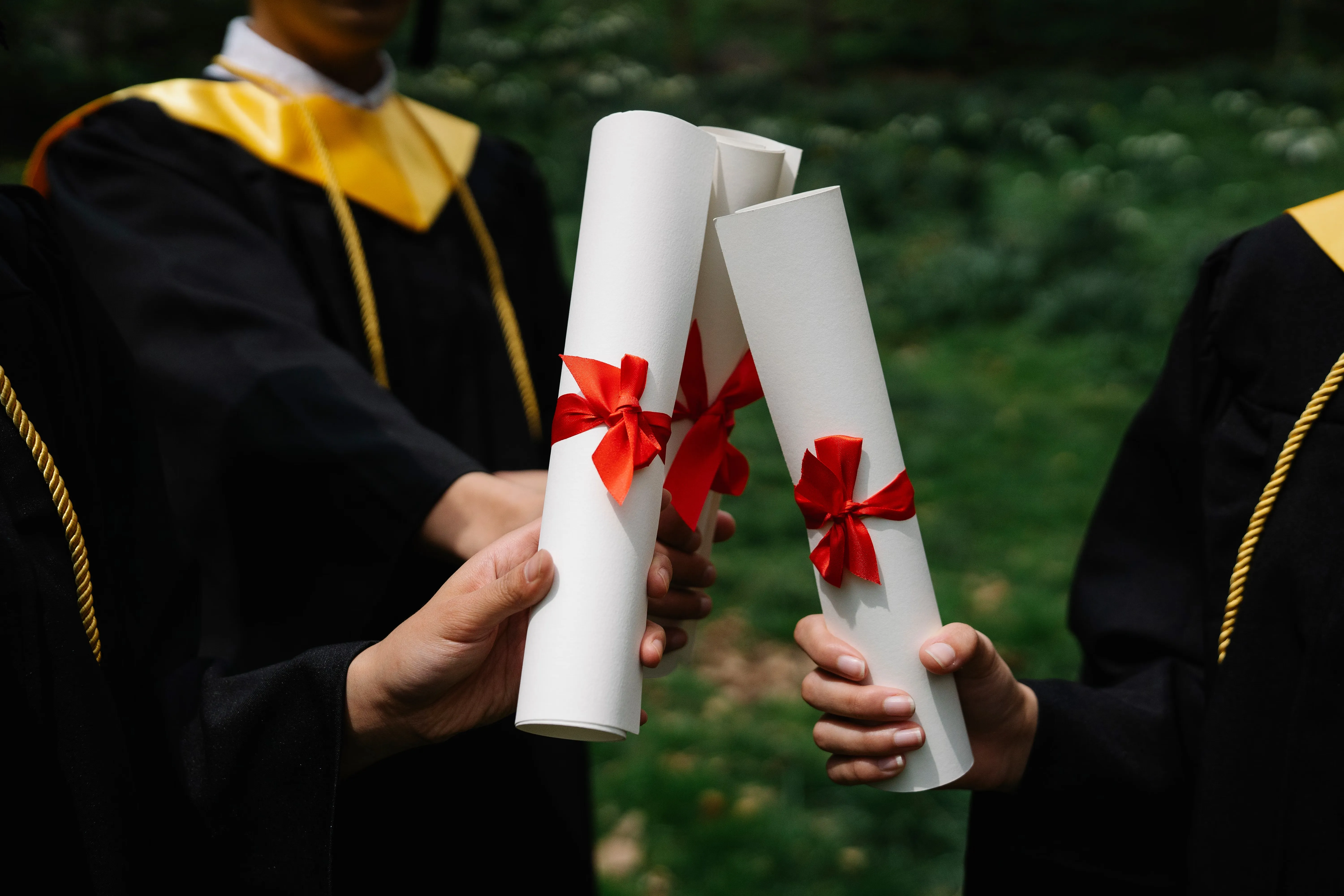Graduados segurando diplomas com fitas vermelhas